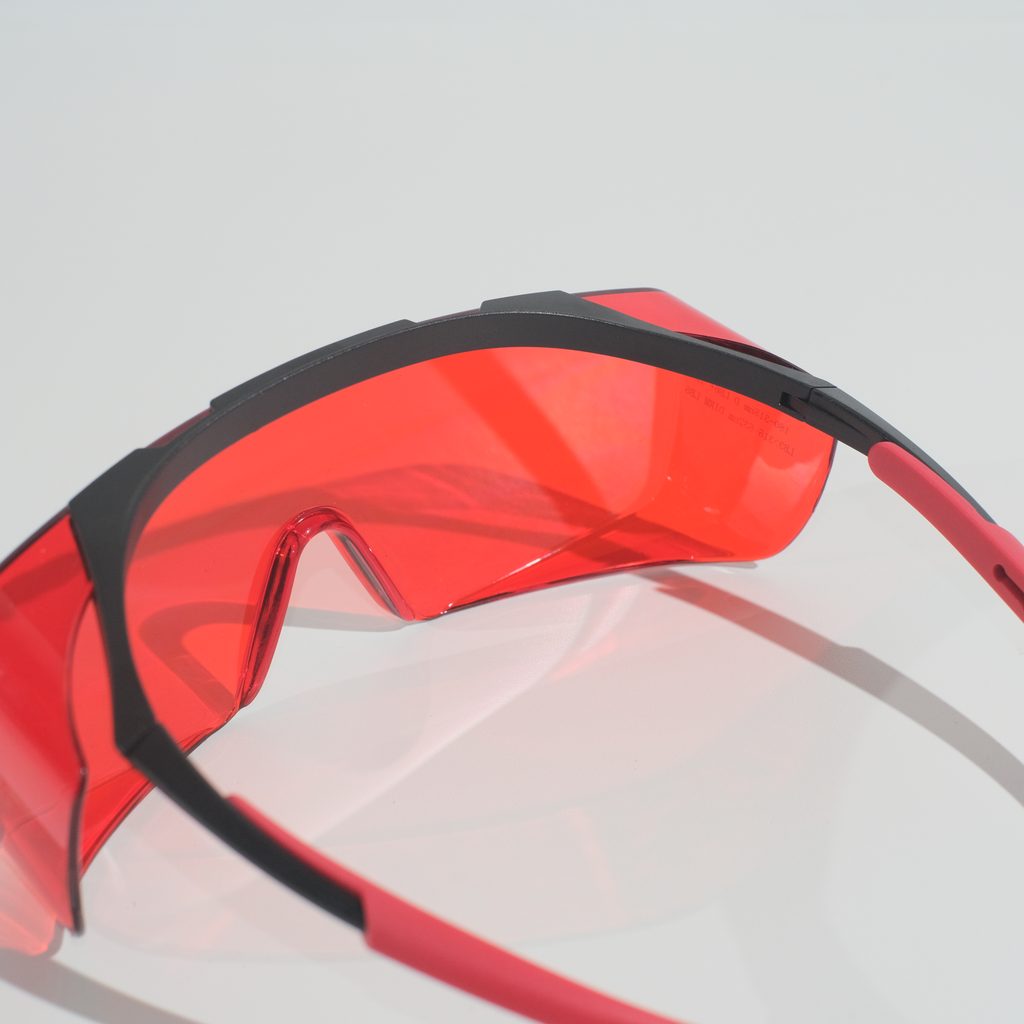 Close view from above and behind the glasses showing the curved red lens running beneath the black brow bar.